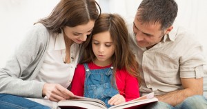 25271828 - mother and father helping their daughter while reading book